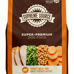 A package of Supreme Source Super-Premium Dog Food with Turkey Meal & Sweet Potato Recipe. The bag is predominantly brown with images of the product contents, which include turkey and sweet potatoes, displayed on the front.
