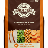 A package of Supreme Source Super-Premium Dog Food with Turkey Meal & Sweet Potato Recipe. The bag is predominantly brown with images of the product contents, which include turkey and sweet potatoes, displayed on the front.