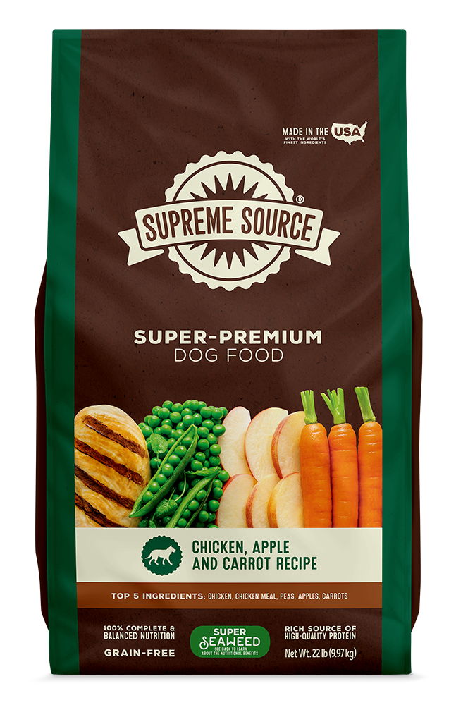 A bag of Supreme Source Premium Dry Dog Food featuring chicken, apple, and carrot as main ingredients. The packaging is predominantly green and brown with images of the mentioned vegetables and a caption that reads 'Grain-Free'.