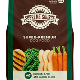 A bag of Supreme Source Premium Dry Dog Food featuring chicken, apple, and carrot as main ingredients. The packaging is predominantly green and brown with images of the mentioned vegetables and a caption that reads 'Grain-Free'.
